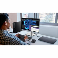 A professional using the Dell U2424HE 23.8" FHD Monitor in a modern workspace, demonstrating its ergonomic design and superior color accuracy for enhanced productivity.