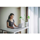 Woman using a Dell laptop with the Dell MS300 Wireless Mouse, showcasing a modern, productive workspace with a plant and natural light.