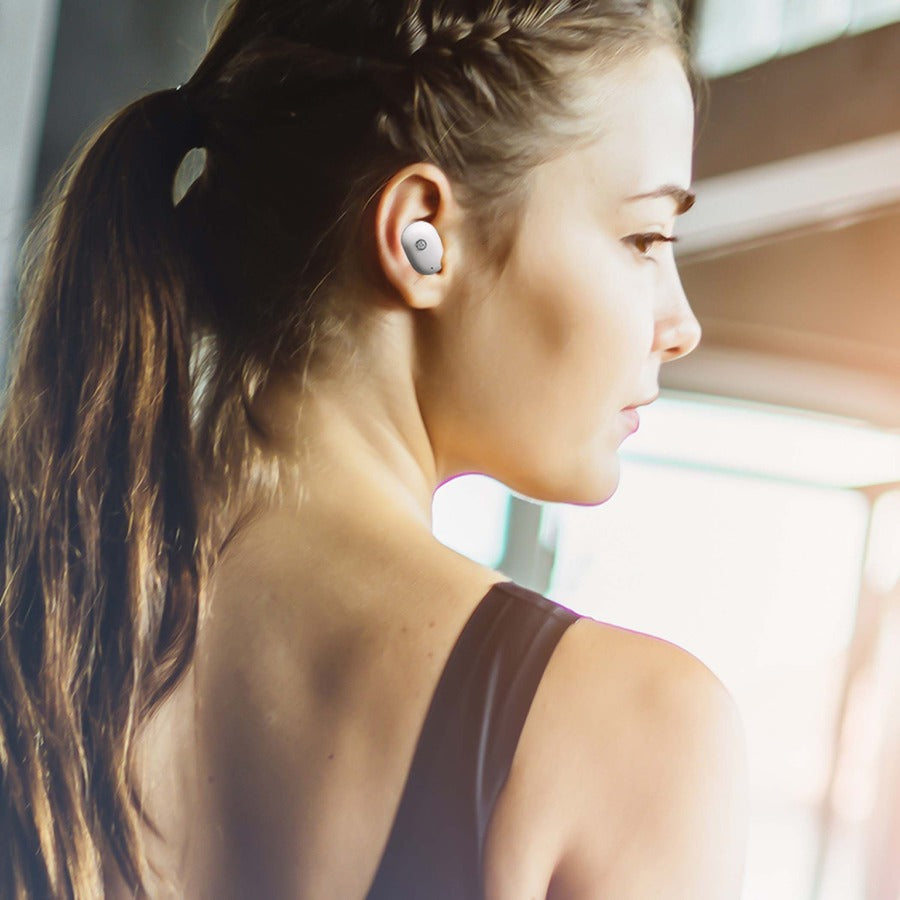 Fitness-focused woman with Morpheus 360 Spire Wireless Earbuds in a modern gym setting, emphasizing style and functionality.