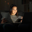 A woman using Morpheus 360 Serenity Wireless Over-Ear Headphones while studying on her laptop, demonstrating the comfort and versatility of the headphones.
