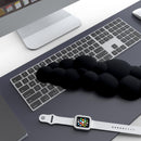 A stylish workstation featuring the CloudWrist Black Memory Foam Wrist Rest by Kokovolta placed next to a keyboard and smartwatch, illustrating the perfect blend of comfort and aesthetics.