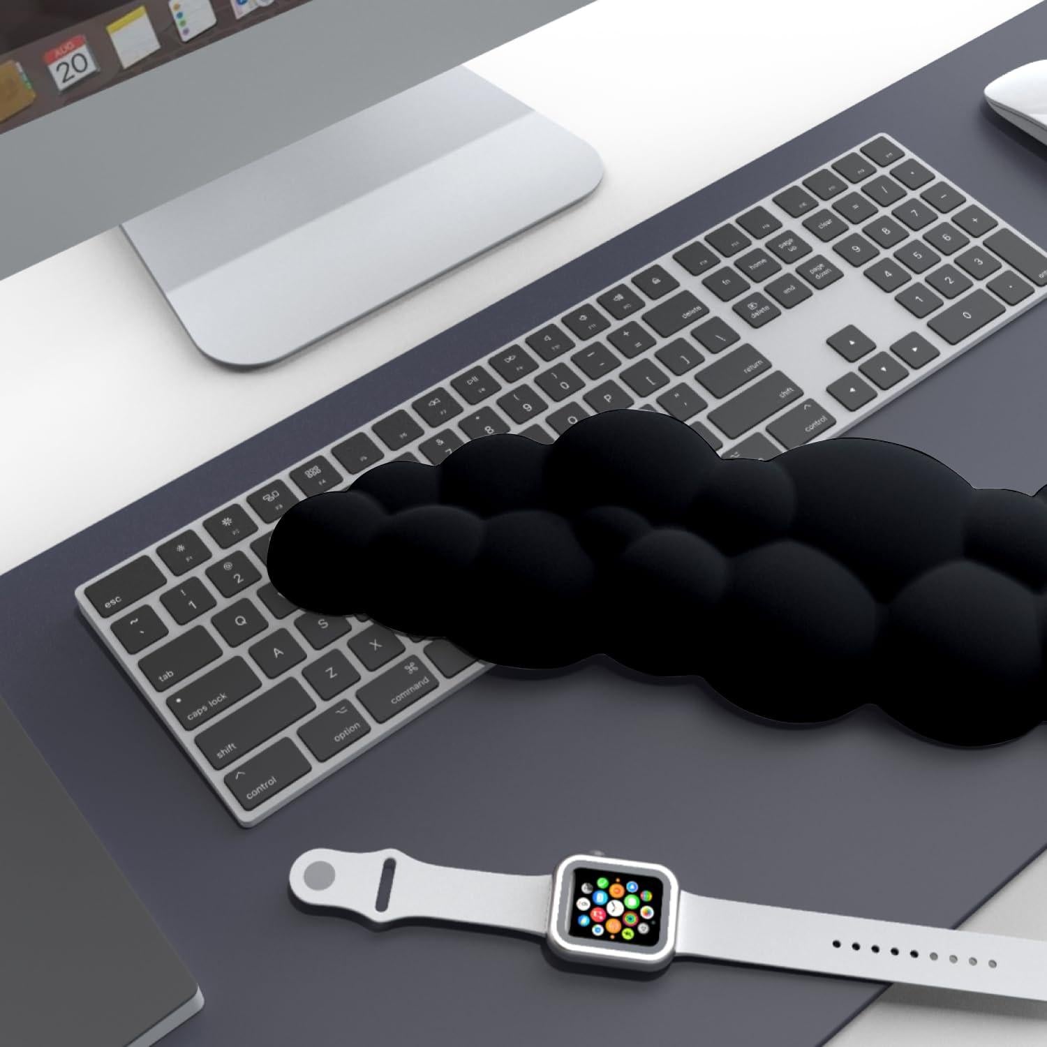 A stylish workstation featuring the CloudWrist Black Memory Foam Wrist Rest by Kokovolta placed next to a keyboard and smartwatch, illustrating the perfect blend of comfort and aesthetics.