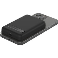 Belkin MagSafe Power Bank 5K wirelessly charging an iPhone, demonstrating seamless magnetic attachment.