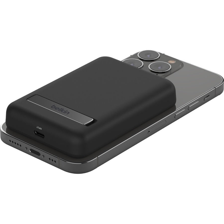 Belkin MagSafe Power Bank 5K wirelessly charging an iPhone, demonstrating seamless magnetic attachment.