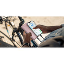 Belkin BoostCharge 20K Power Bank in use outdoors, charging a smartphone while a cyclist navigates, exemplifying convenience and portability for active lifestyles.