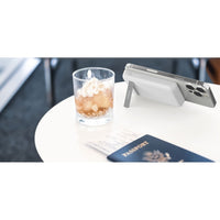 Experience the Belkin BoostCharge Magnetic Power Bank 5000mAh with Stand for iPhone, elegantly placed on a table next to a refreshing drink, showcasing its sleek and functional design for on-the-go charging.